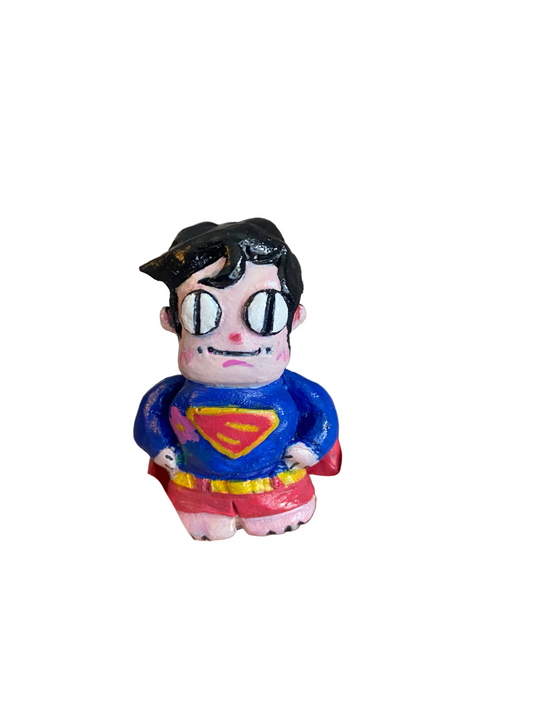Hand holding a small superman figurine with a colorful design against a blurred background