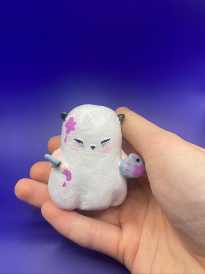 Hand holding a ghost with a paint brush and palette on a blue background