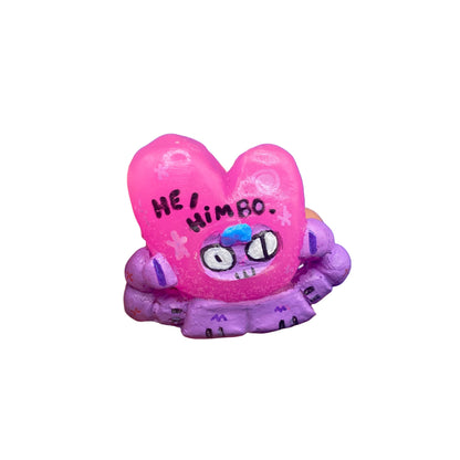 Pink and purple heart-shaped figure with 'HE IS HIMBO' text on a white background