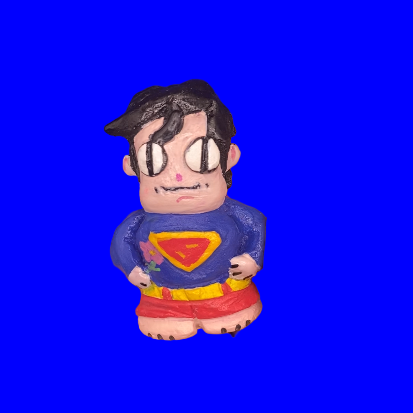 Hand holding a small figurine of a character in a superhero costume against a blue background
