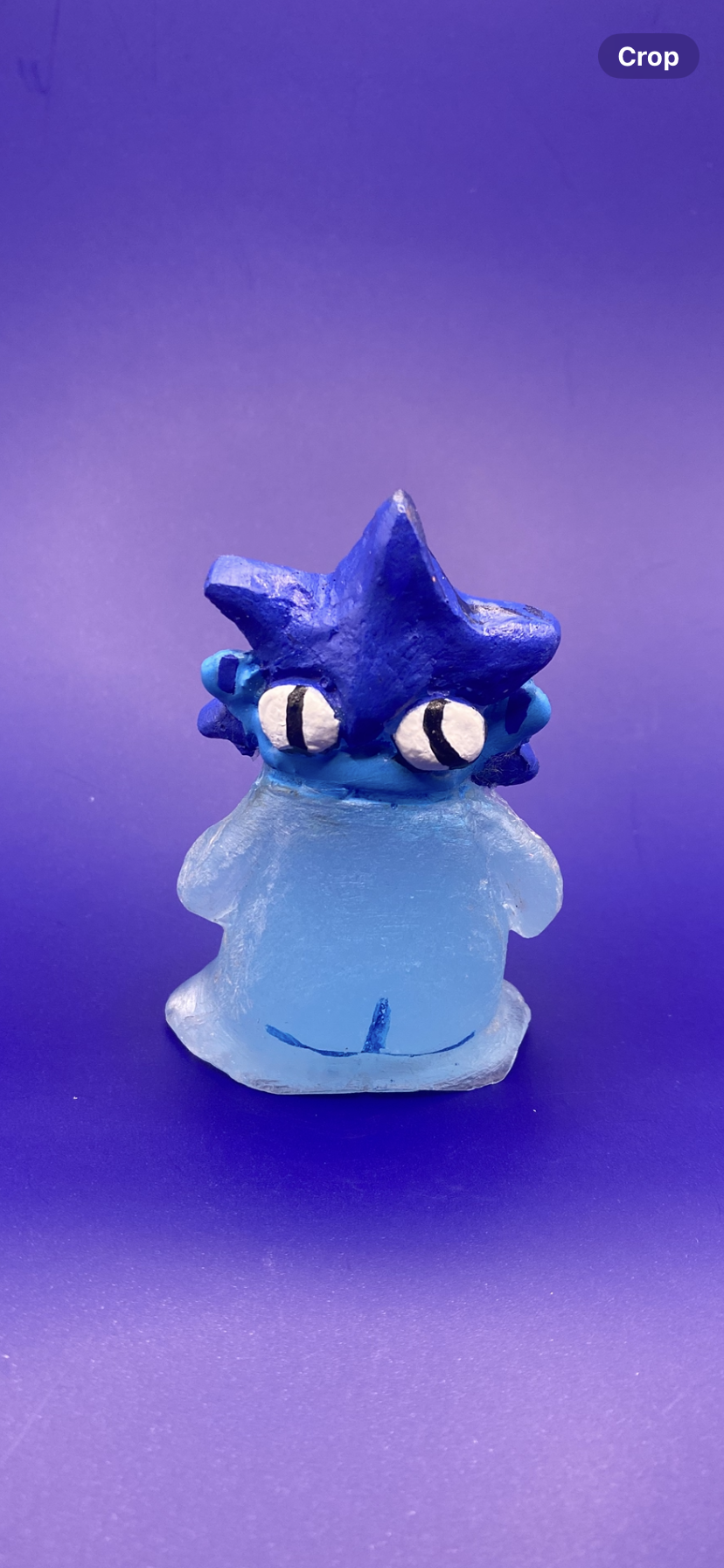 Blue cartoon-like figurine with large eyes on a purple background