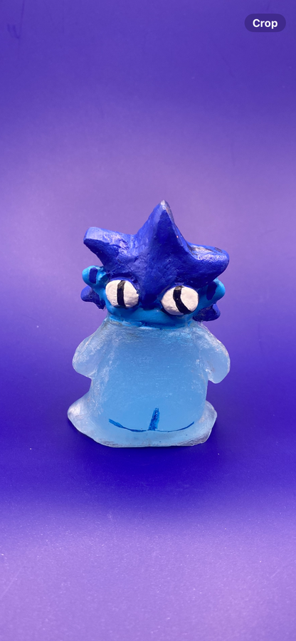Blue cartoon-like figurine with large eyes on a purple background