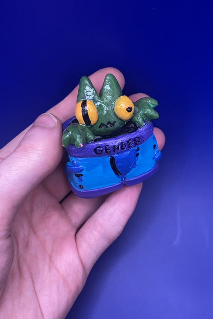 Small figurine of a creature with a blue underwear held in a hand against a blue background