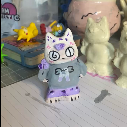 Small figurine with a cat-like design on a desk with stationery items.